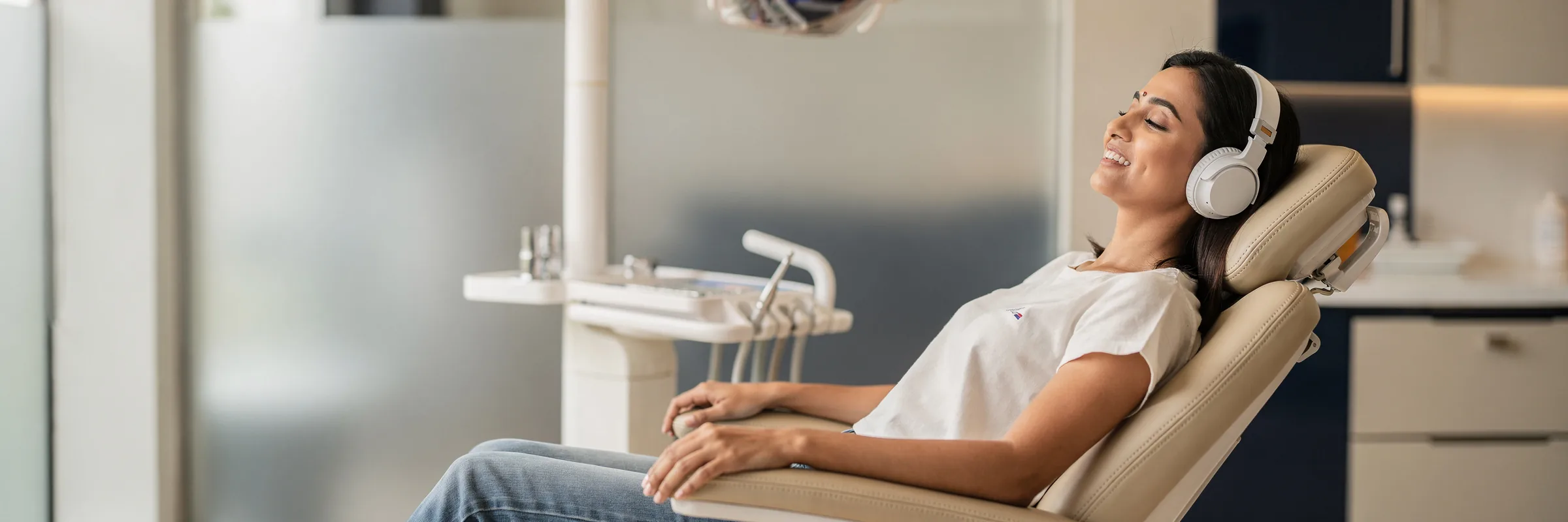 Illustrative picture: a woman relaxed in a dental chair wearing headphones